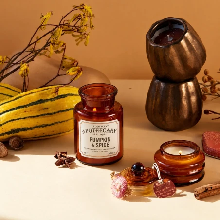 Vela Paddywax Apothecary Pumpkin + Spice encendida en un ambiente otoñal con calabazas y especias
