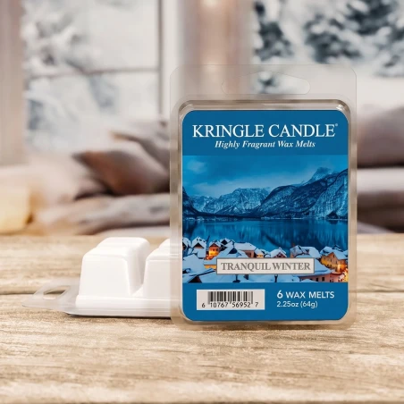 Wax melts Kringle Candle Tranquil Winter 64 g sobre una mesa de madera rústica en un salón invernal con vistas a la nieve