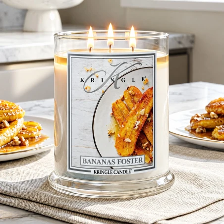Vela Kringle Candle Bananas Foster de 3 mechas encendida en una cocina con plátanos y postre de plátano caramelizado