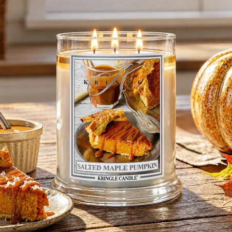 Vela Kringle Candle Salted Maple Pumpkin de 3 mechas encendida en una mesa de madera con tarta de calabaza