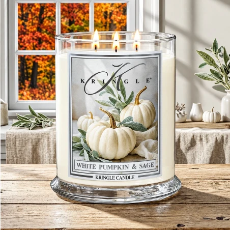 Vela Kringle Candle White Pumpkin & Sage de 3 mechas encendida en una mesa rústica con salvia y calabazas blancas