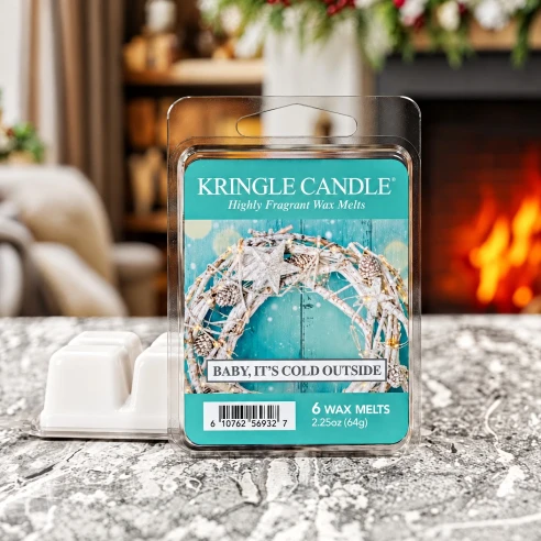 Wax melts Kringle Candle Baby It's Cold Outside 64 g sobre una superficie de mármol junto a la chimenea en un ambiente invernal