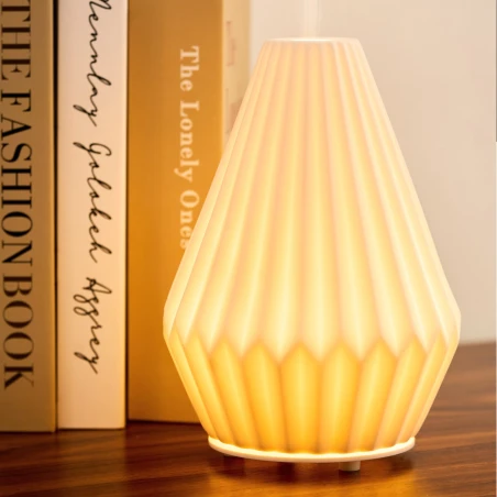Difusor eléctrico Maison Berger Cône encendido junto a unos libros
